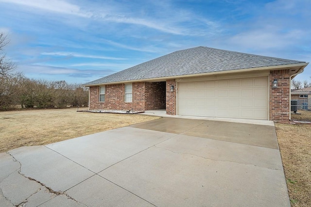 ranch-style home with brick siding, a shingled roof, a garage, driveway, and a front lawn