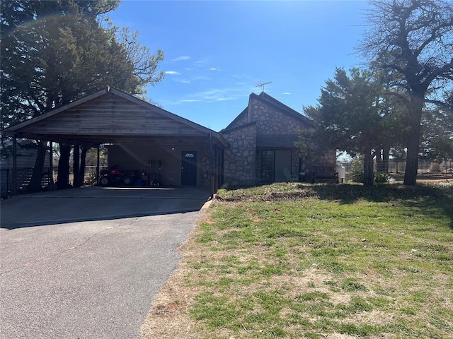 view of front of property featuring a front lawn, stone siding, and driveway