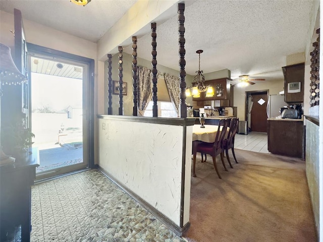 entryway with light carpet, a ceiling fan, baseboards, and a textured ceiling