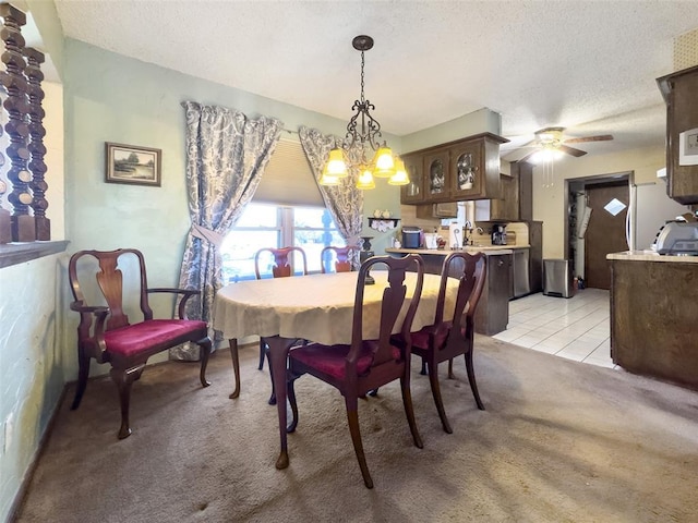 dining area with a textured ceiling, light colored carpet, light tile patterned floors, and ceiling fan with notable chandelier