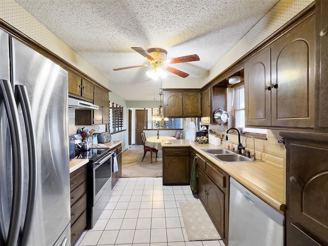 kitchen featuring a ceiling fan, a sink, stainless steel appliances, light countertops, and under cabinet range hood