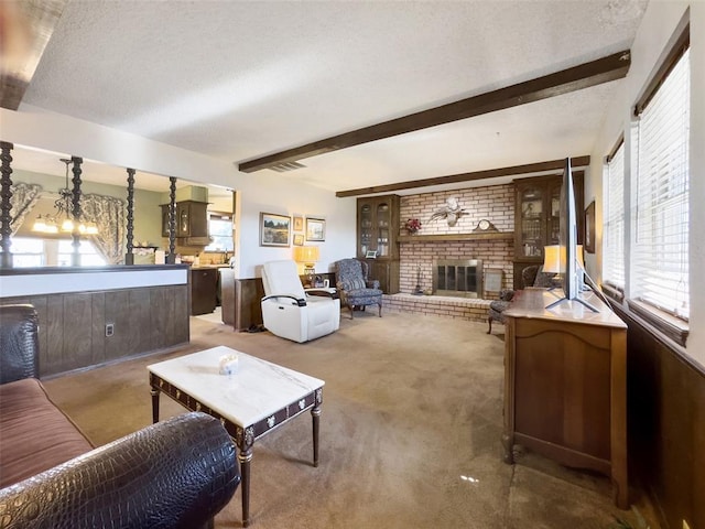 carpeted living area featuring beamed ceiling, plenty of natural light, a textured ceiling, and a fireplace