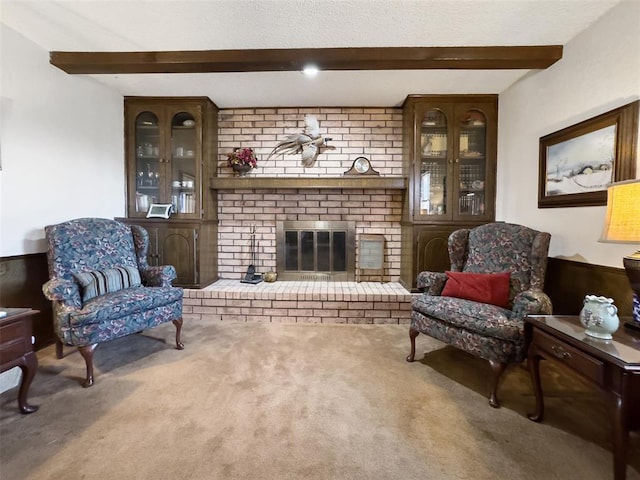 living room with beamed ceiling, carpet, a brick fireplace, and a textured ceiling