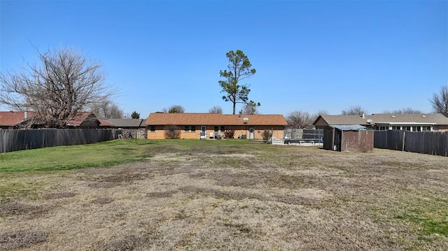 back of property with an outbuilding, a yard, a fenced backyard, and a storage unit