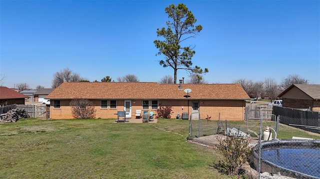 rear view of property featuring brick siding, a fenced backyard, a yard, a patio, and a gate