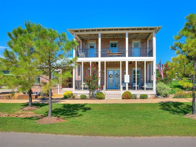 view of front of house with brick siding, a balcony, covered porch, french doors, and a front yard