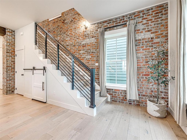 staircase featuring brick wall and hardwood / wood-style flooring