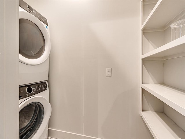 laundry area with laundry area, stacked washing maching and dryer, and baseboards