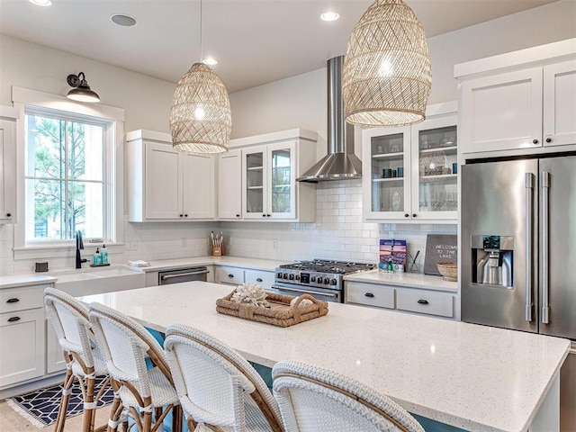 kitchen featuring light stone counters, a breakfast bar area, a sink, wall chimney range hood, and high end appliances