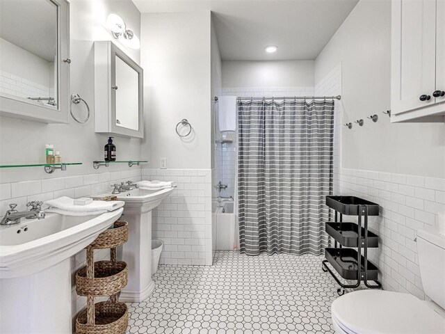 full bathroom featuring a wainscoted wall, tile walls, and toilet