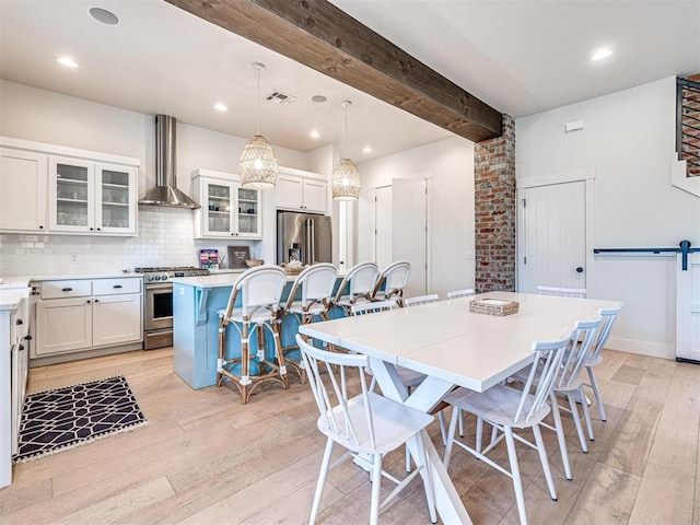 dining room featuring beam ceiling, recessed lighting, visible vents, a barn door, and light wood-type flooring