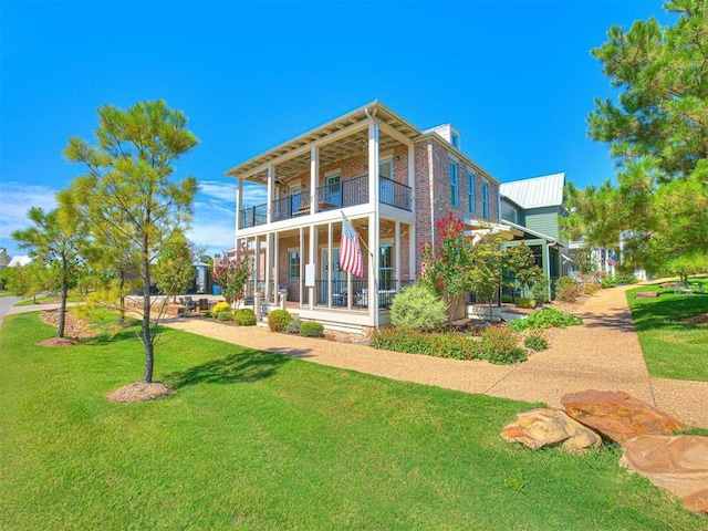 back of property with a yard, brick siding, and a balcony