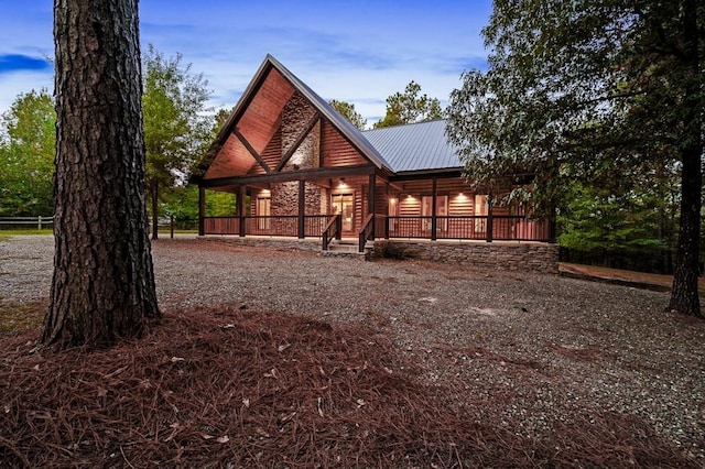 rear view of property featuring faux log siding, covered porch, and metal roof