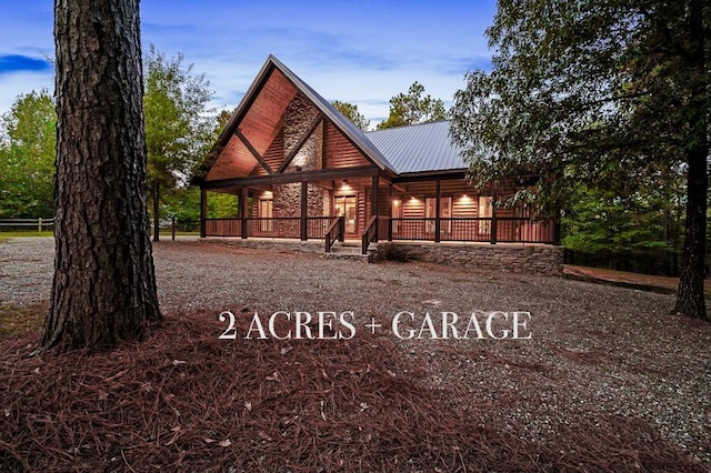 rear view of house with faux log siding, covered porch, and metal roof