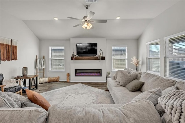 living room featuring visible vents, a glass covered fireplace, baseboards, ceiling fan, and vaulted ceiling