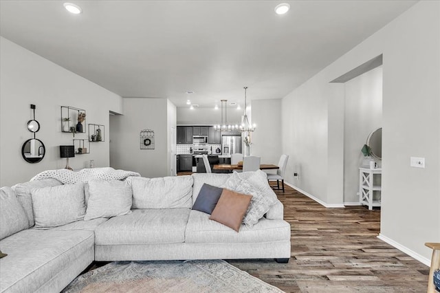 living area featuring recessed lighting, baseboards, dark wood-style flooring, and a chandelier