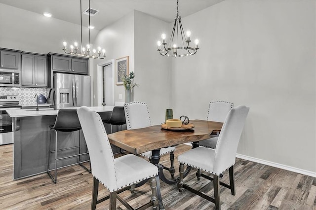 dining area with light wood finished floors, visible vents, an inviting chandelier, and baseboards