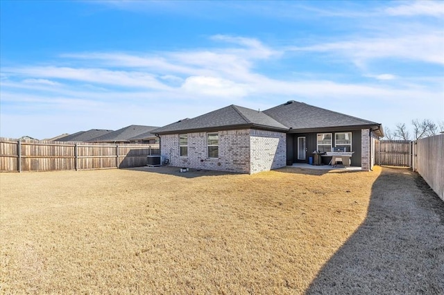 back of house with a patio, cooling unit, a fenced backyard, a lawn, and brick siding