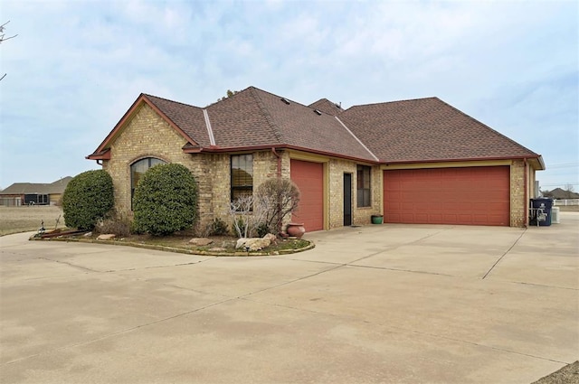 view of front of home featuring concrete driveway, brick siding, a garage, and roof with shingles