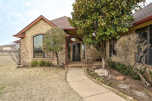 view of front of home with stone siding and roof with shingles