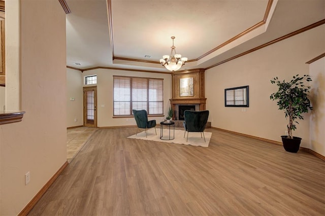 unfurnished room featuring a notable chandelier, light wood-style flooring, a raised ceiling, and baseboards