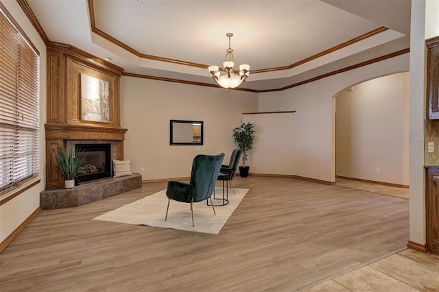 unfurnished room with a raised ceiling, ornamental molding, arched walkways, and a premium fireplace