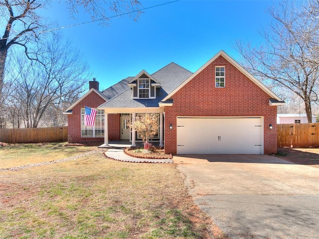 traditional-style house featuring driveway, fence, a front lawn, and brick siding