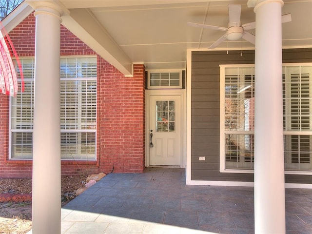 entrance to property featuring a ceiling fan and brick siding