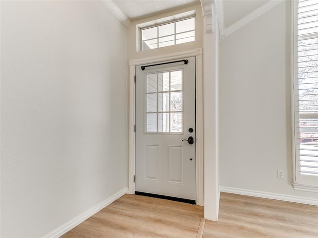 doorway with ornamental molding, light wood-type flooring, and baseboards