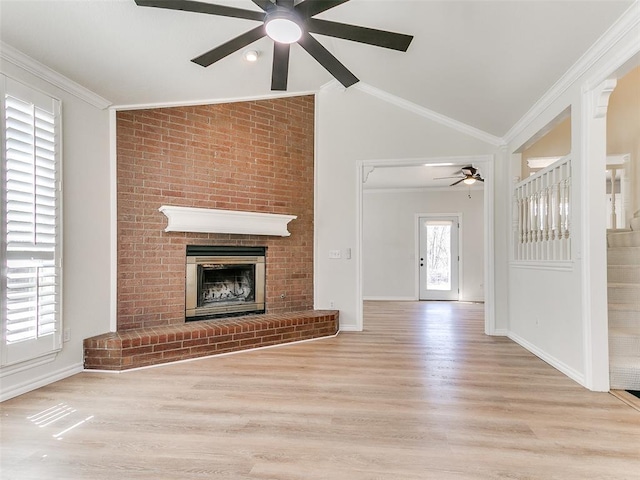 unfurnished living room with ornamental molding, a brick fireplace, vaulted ceiling, and a ceiling fan