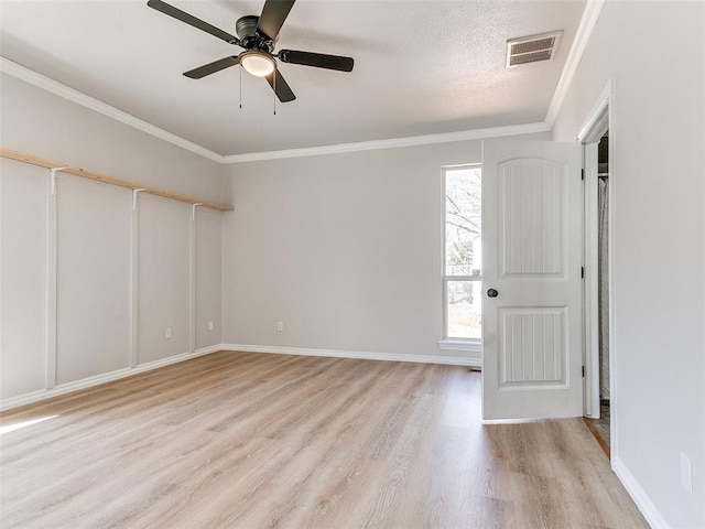 unfurnished room with baseboards, visible vents, crown molding, and light wood finished floors