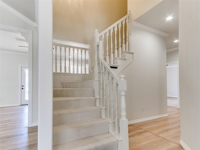 stairway with crown molding, baseboards, and wood finished floors