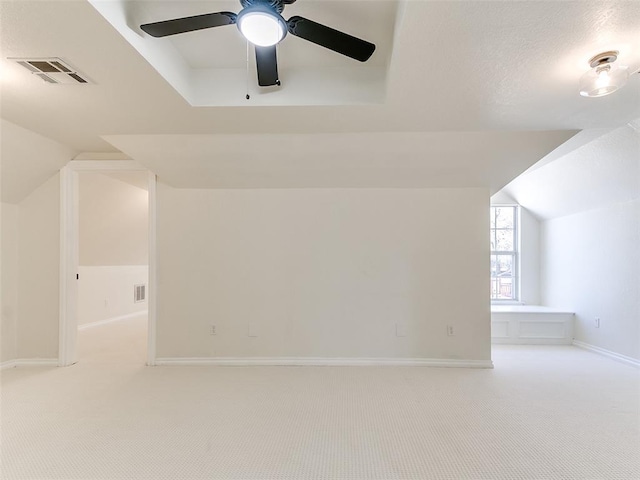 additional living space with vaulted ceiling, baseboards, visible vents, and light colored carpet