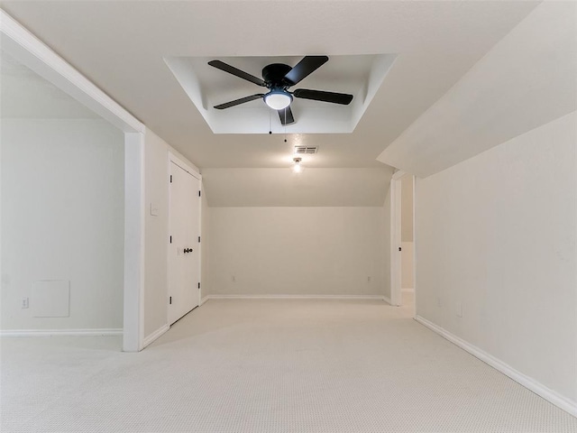 spare room with visible vents, baseboards, light colored carpet, ceiling fan, and a tray ceiling