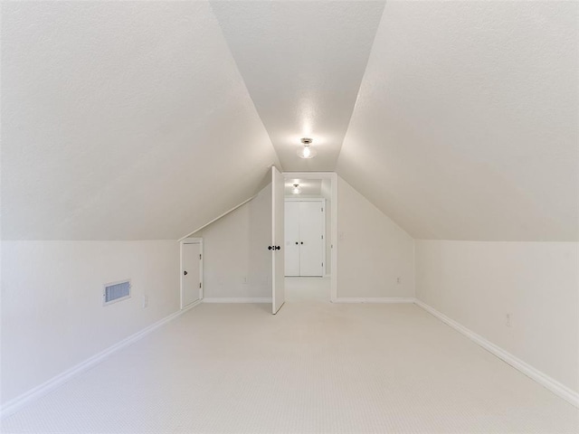 bonus room with lofted ceiling, baseboards, visible vents, and light colored carpet