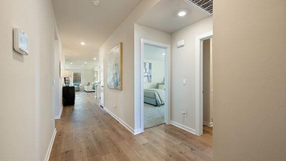 corridor with recessed lighting, visible vents, baseboards, and wood finished floors