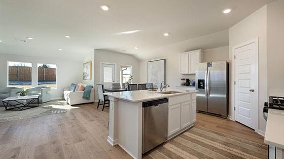 kitchen with open floor plan, stainless steel appliances, a sink, and light wood-style flooring