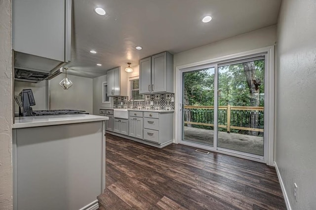 kitchen featuring recessed lighting, gray cabinetry, dark wood-type flooring, light countertops, and backsplash