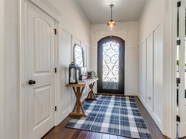 entryway with baseboards, dark wood-type flooring, and a decorative wall