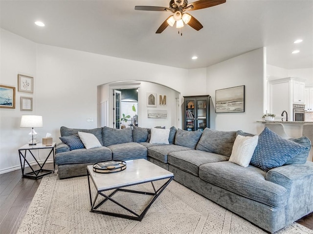 living room with wood finished floors, a ceiling fan, baseboards, recessed lighting, and arched walkways