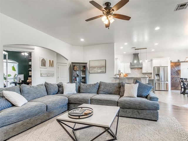 living area featuring visible vents, wood finished floors, recessed lighting, arched walkways, and ceiling fan