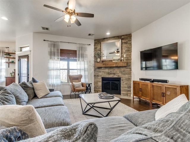 living room featuring visible vents, a fireplace, a ceiling fan, and wood finished floors