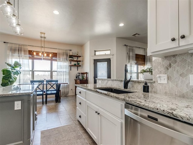 kitchen featuring a sink, backsplash, stainless steel dishwasher, and white cabinets