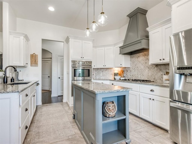 kitchen featuring premium range hood, open shelves, a sink, appliances with stainless steel finishes, and decorative backsplash