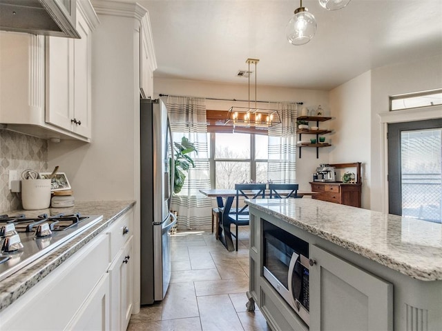 kitchen featuring backsplash, pendant lighting, light stone counters, white cabinets, and stainless steel appliances