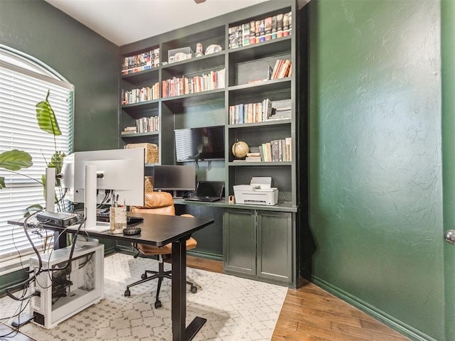 office space with light wood-style floors, baseboards, and a textured wall