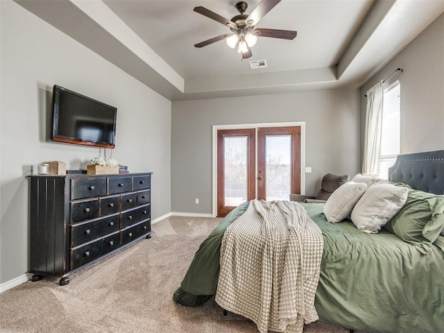 carpeted bedroom featuring a tray ceiling, access to outside, french doors, and visible vents