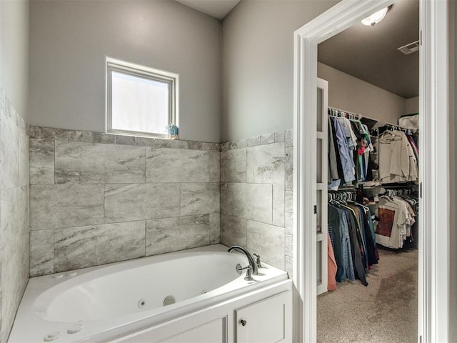 full bathroom with visible vents, a walk in closet, and a whirlpool tub