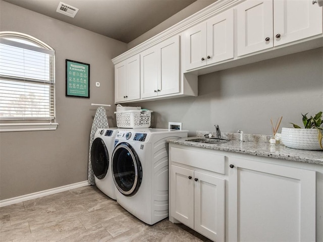 laundry area featuring visible vents, a sink, washer and dryer, cabinet space, and baseboards