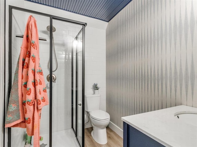 bathroom featuring wood finished floors, toilet, a stall shower, and vanity